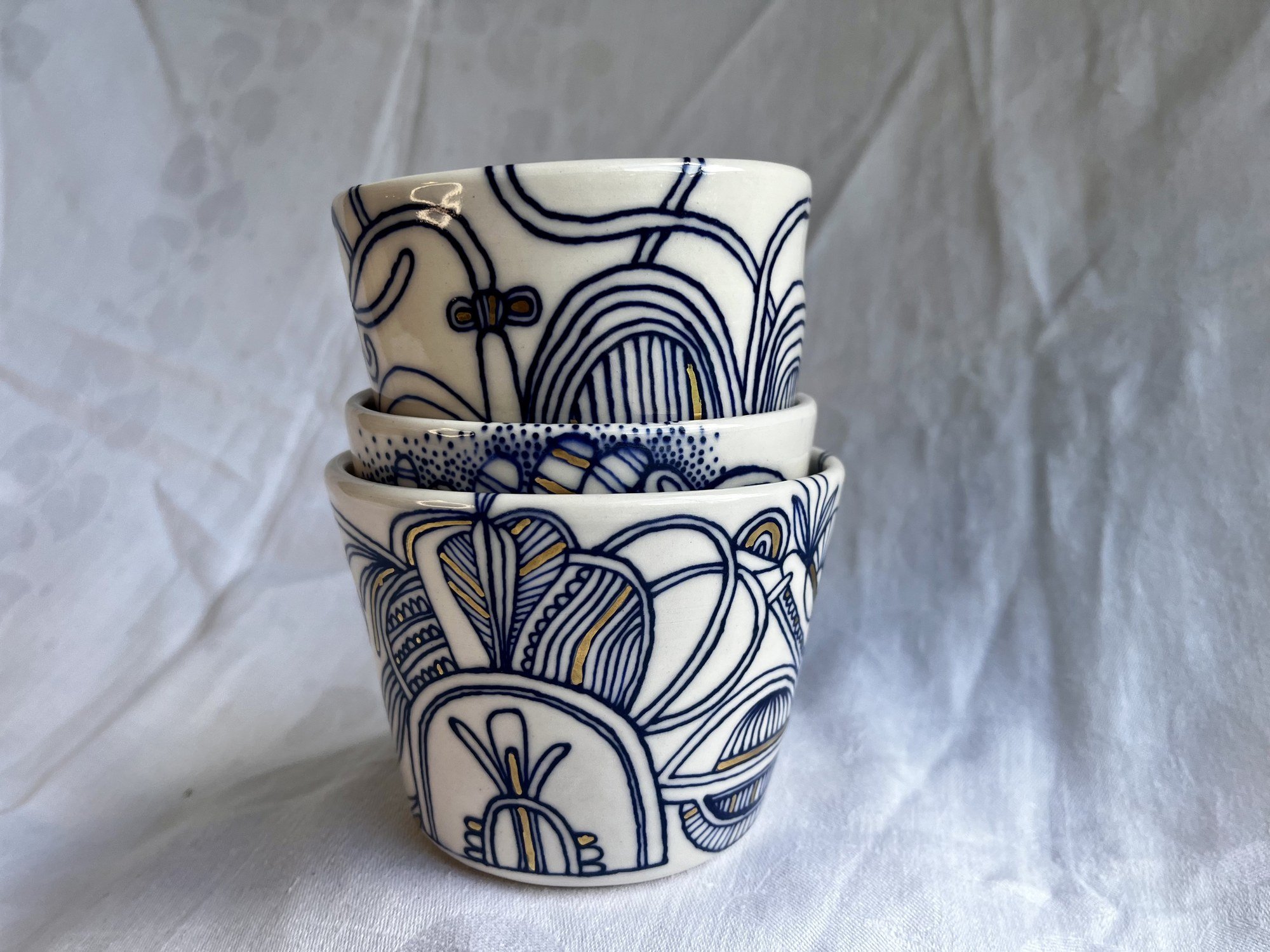 Stack of three hand-thrown porcelain tumblers hand-painted in cobalt blue by Cypress Knees Ceramics