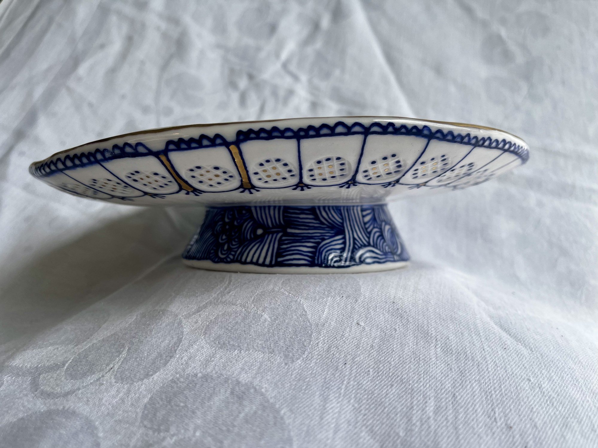 Side view of hand-thrown porcelain serving dish No. 002 showing its footed pedestal