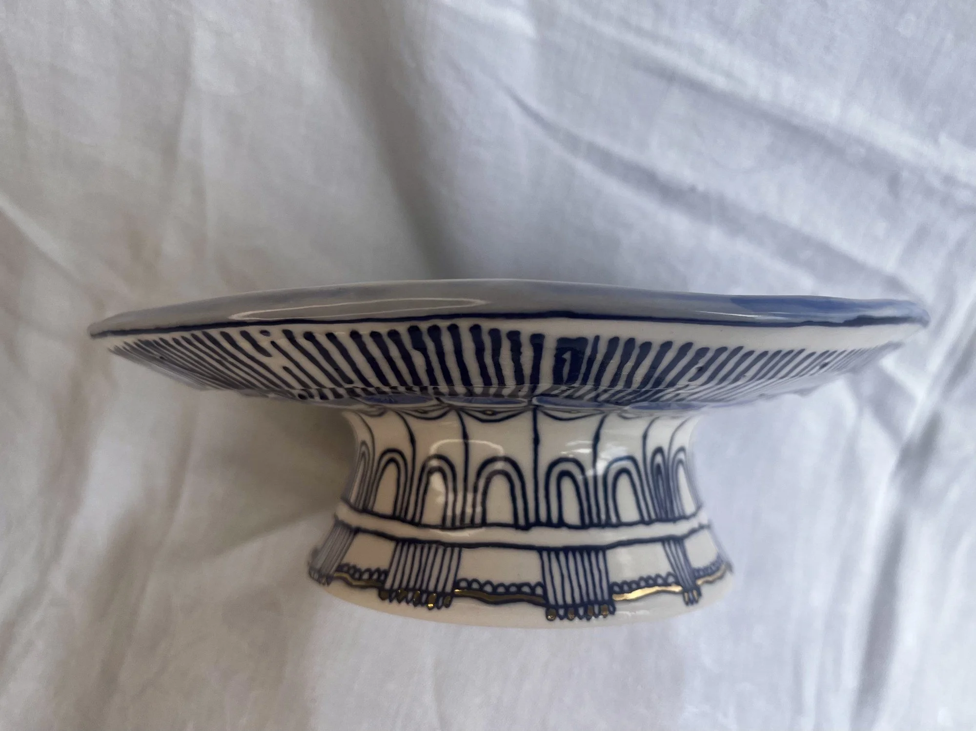 Side view of hand-thrown porcelain serving dish No. 001 showing its footed pedestal