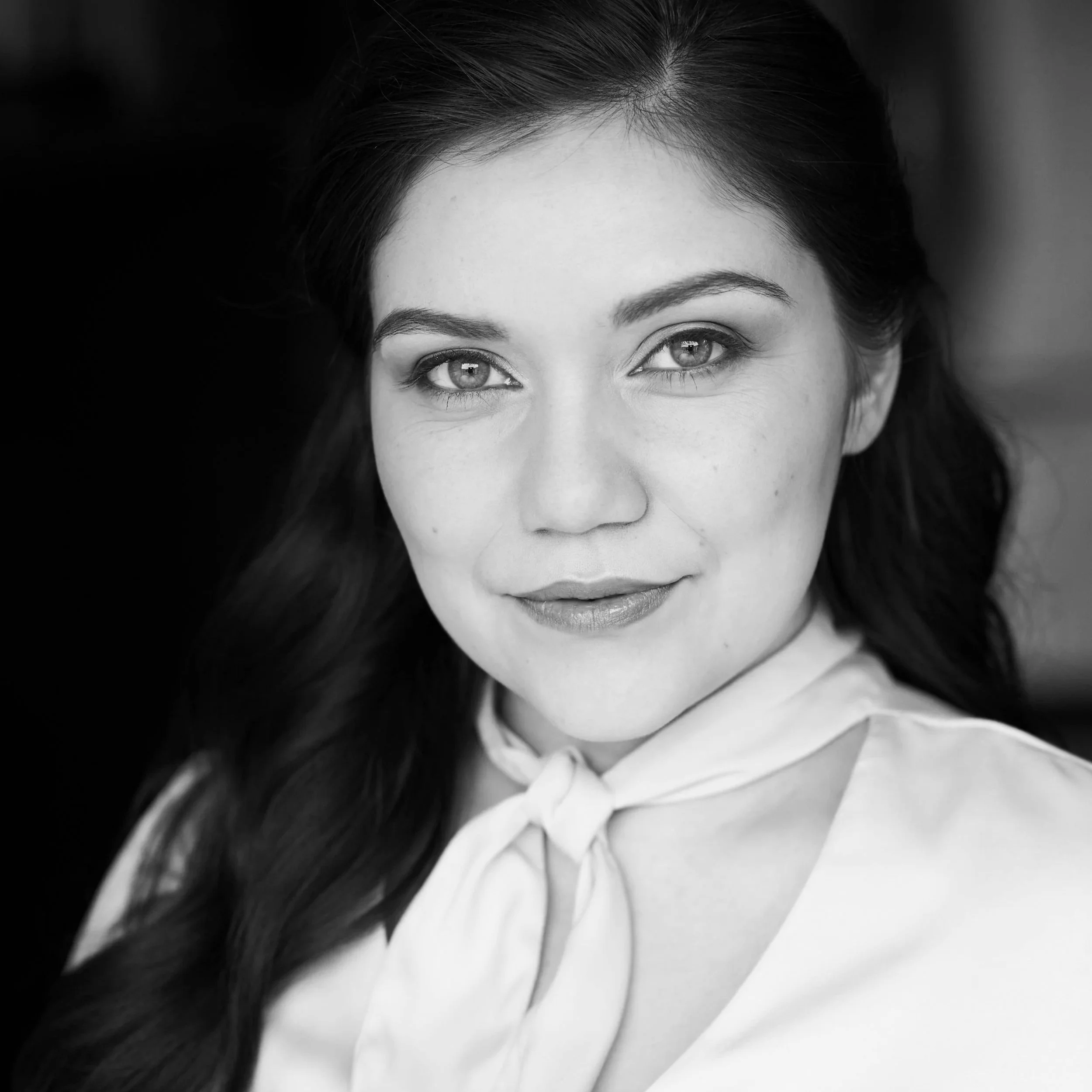 Close-up black-and-white portrait of a woman with dark hair and light-colored eyes.