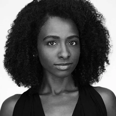 Black and white portrait of a woman with curly hair and a slight smile.