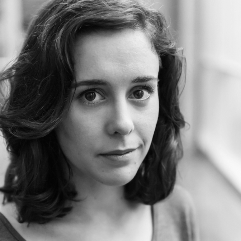 A black and white close-up portrait of a young woman with wavy hair and a soft expression, looking directly at the camera.