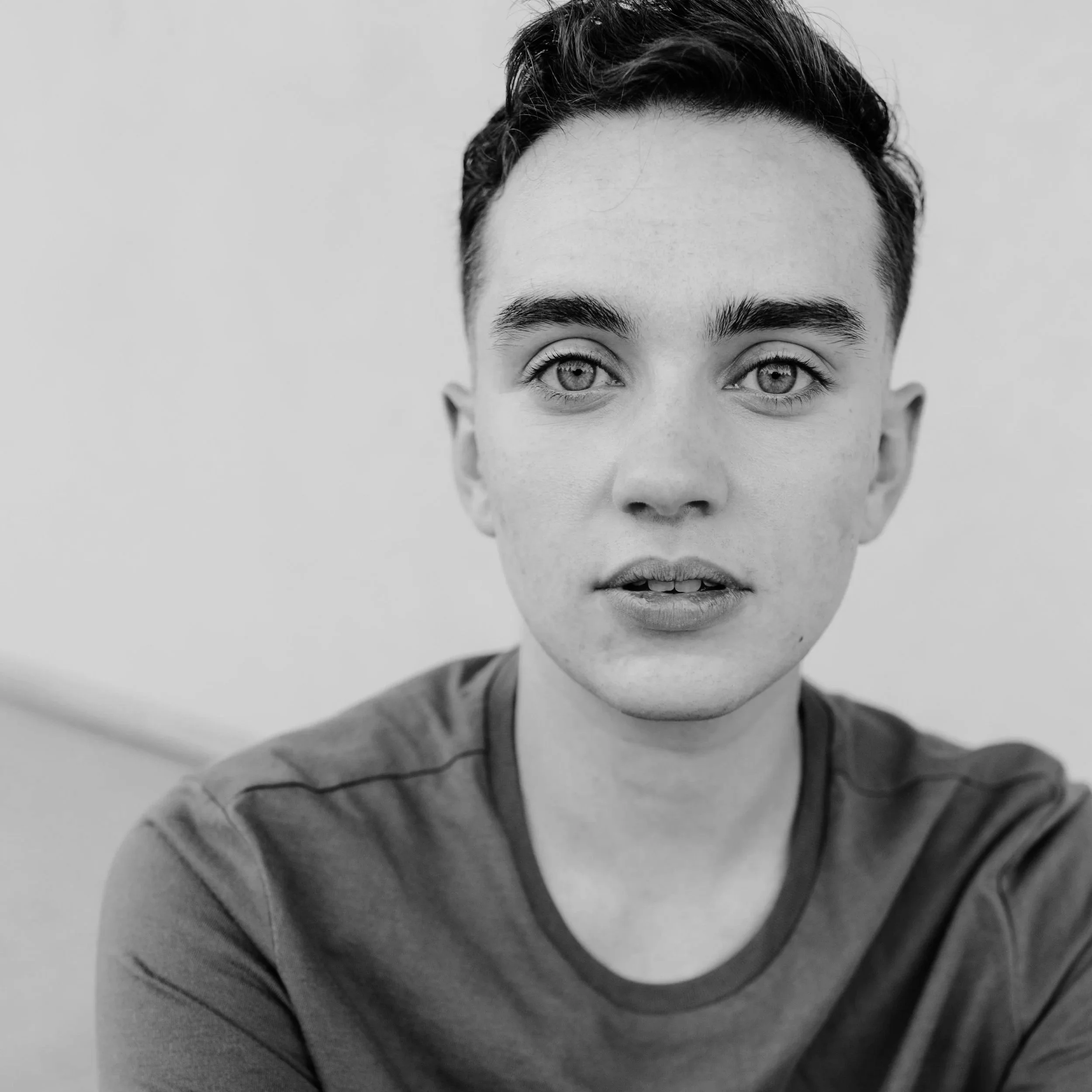 Close-up black-and-white photograph of a person's face, with short dark hair.