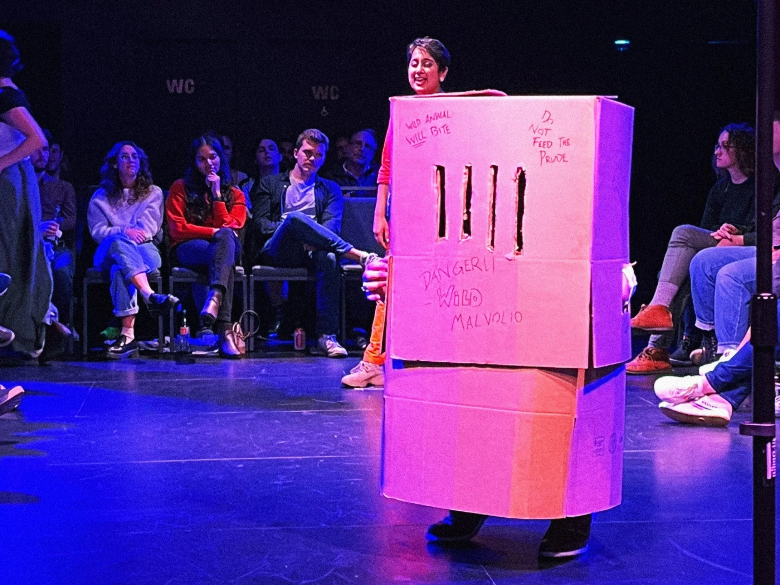 A person standing inside a large with handwritten notes in black marker, including 'Wild Animal. Will Bite,' 'Not Feed the Prude,' and 'Danger!'