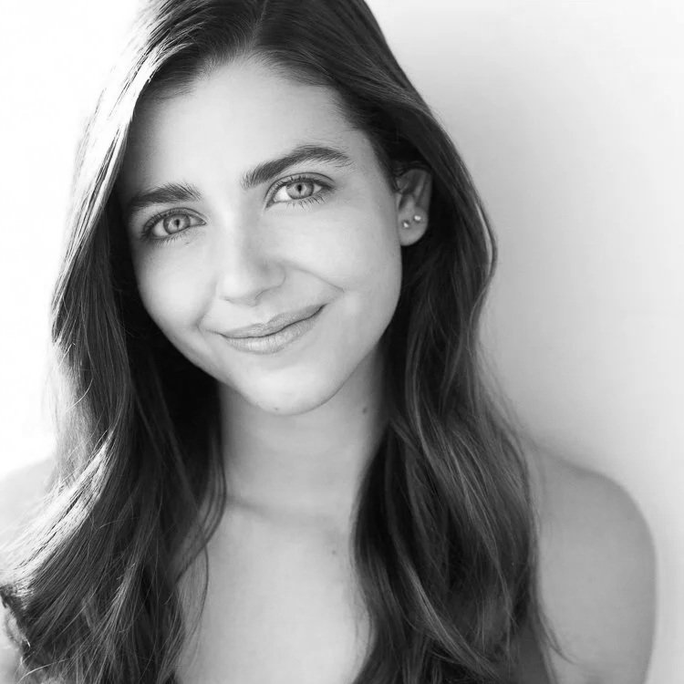 Black and white portrait of a young woman with long hair, smiling, and looking at the camera.