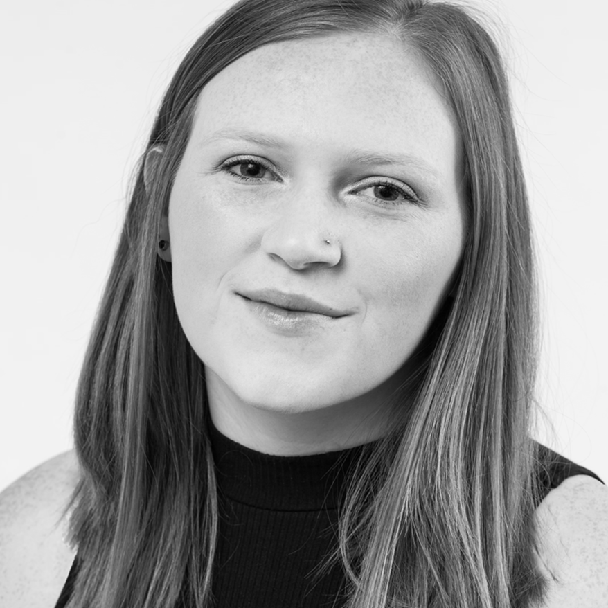 Black and white portrait of a person with straight, shoulder-length hair, wearing a sleeveless top, looking at the camera with a gentle smile.