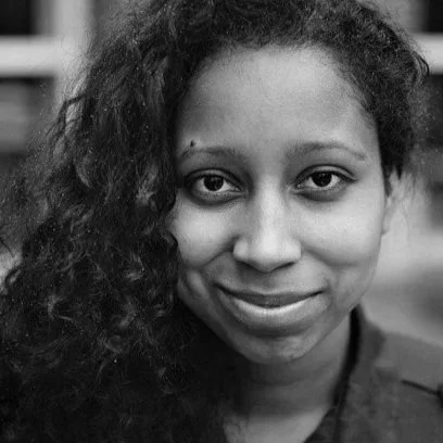 Close-up black and white portrait of a woman with curly hair smiling.
