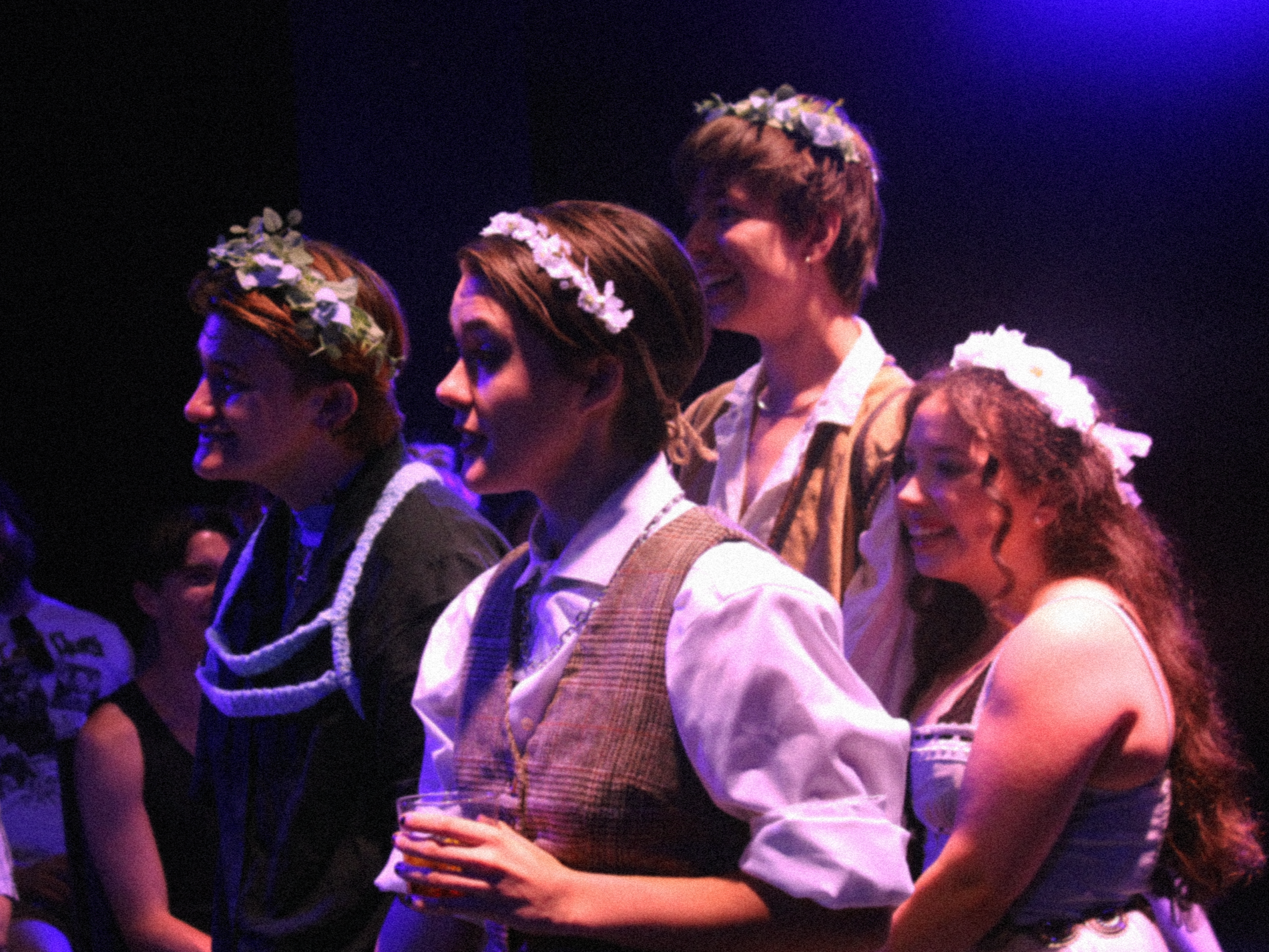 Group of actors wearing flower crowns, standing together.