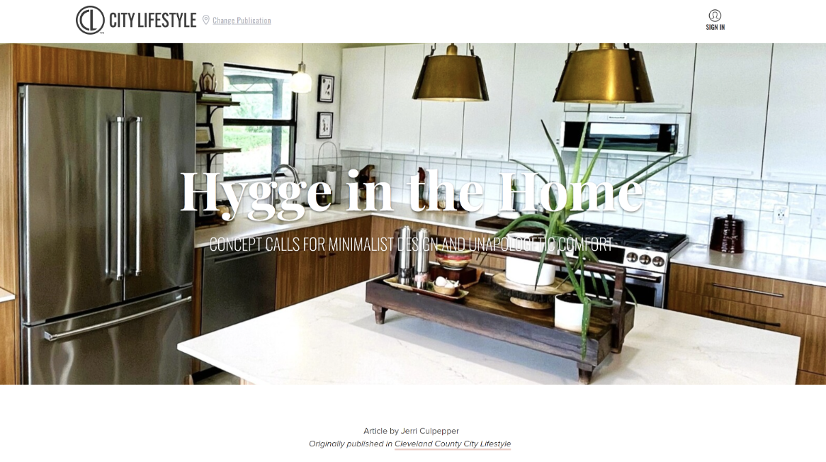 Modern kitchen with white cabinets, stainless steel refrigerator, and wooden accents. Decor includes a potted plant, pendant lights, and minimal accessories. Contains oven, microwave, and a white island counter.