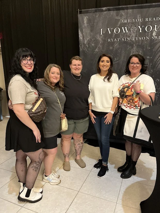 Five women standing together in front of a promotional poster for the musical 'Come From Away', smiling and posing for a photo.