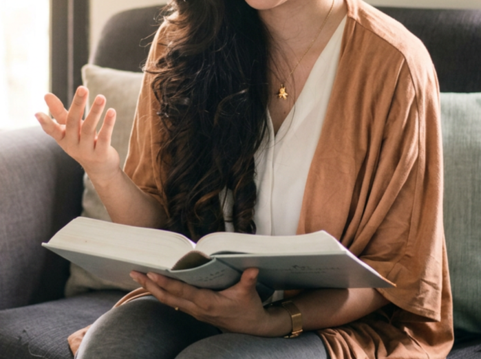 Woman reading an open book while seated on a couch