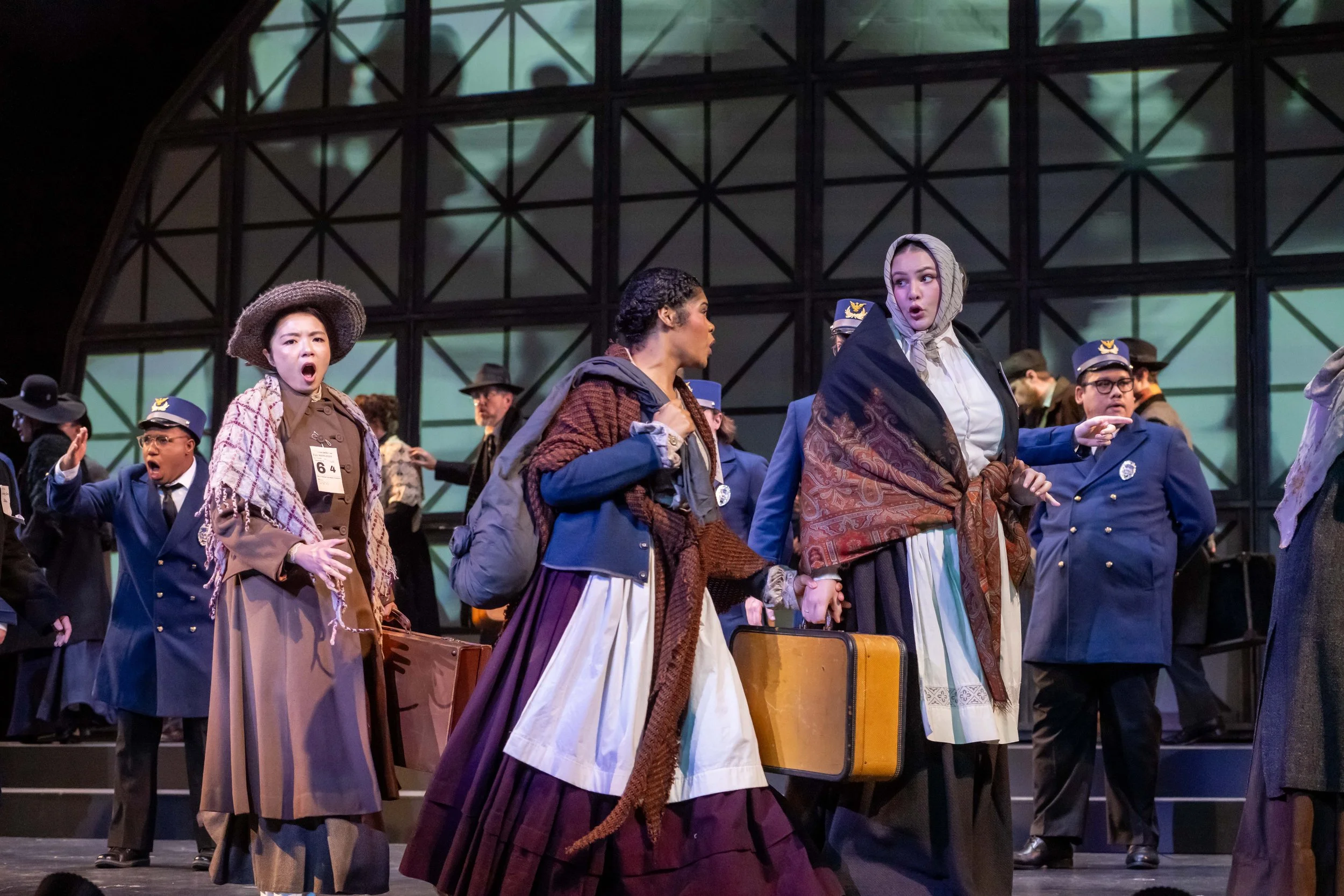 Actors in costumes performing on stage, with expressions of surprise or concern, in a theater setting.