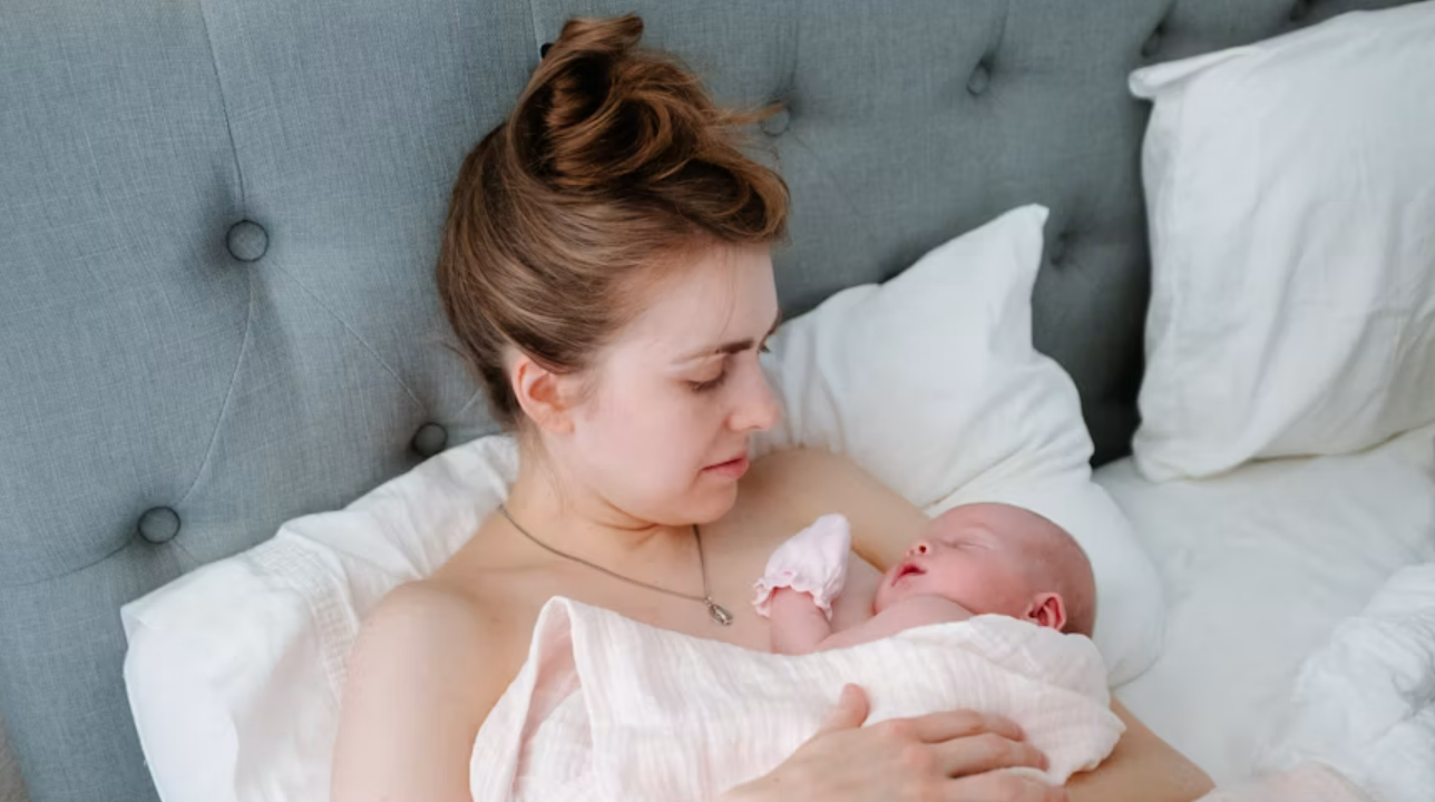 a postpartum mother holding her new baby in bed