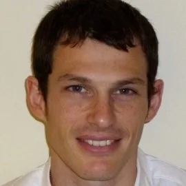 Portrait of a young man with dark hair smiling at the camera.