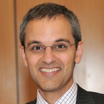 Portrait of a smiling man wearing glasses and a suit.