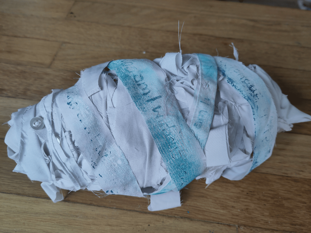 White cotton cocoon made of strips of cotton printed words in blue read 'who am I without you?'