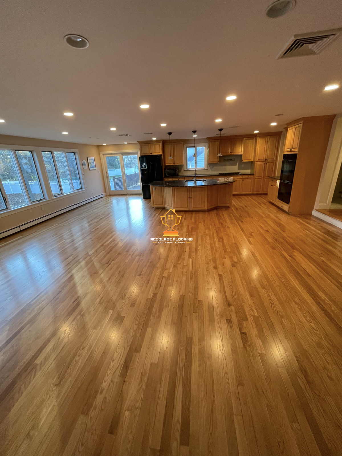 Spacious open-concept living area and kitchen with hardwood floors, large windows, and modern kitchen cabinets.