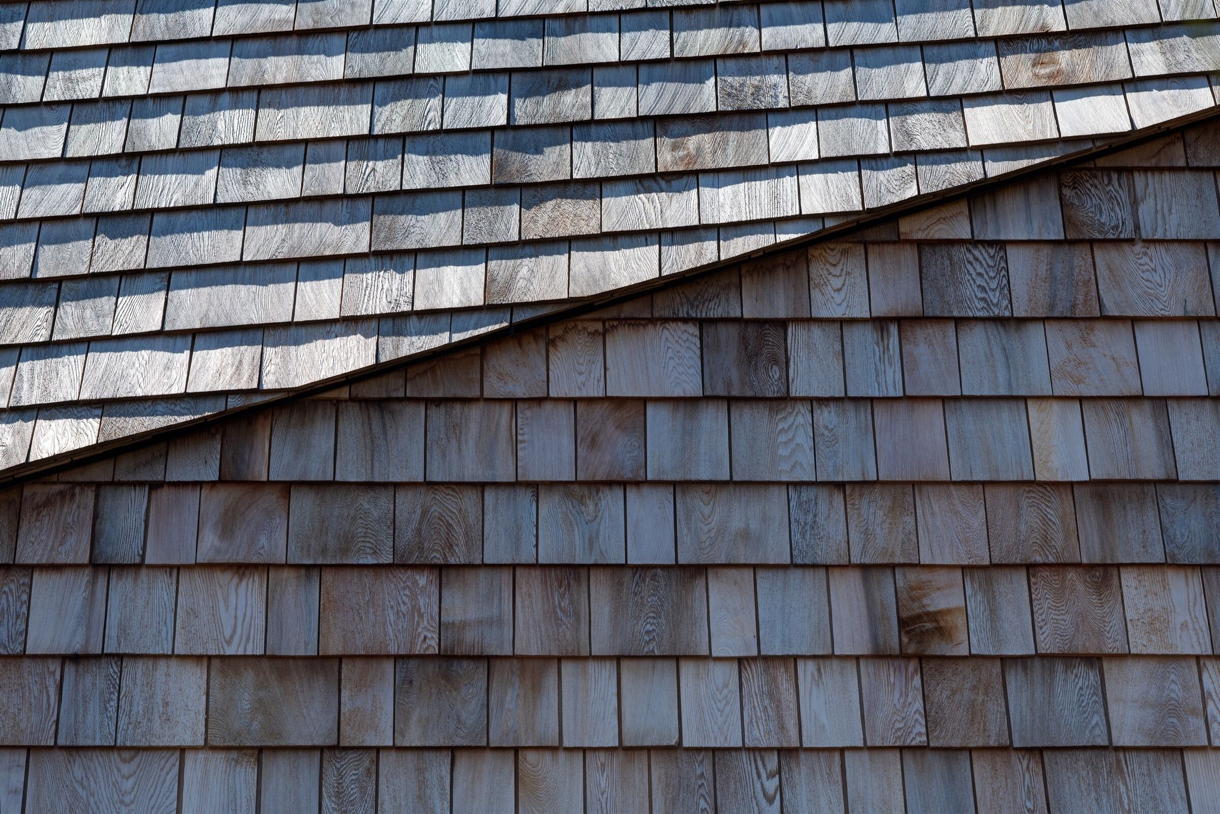 Close-up of a wooden shingle roof with overlapping rectangular shingles.