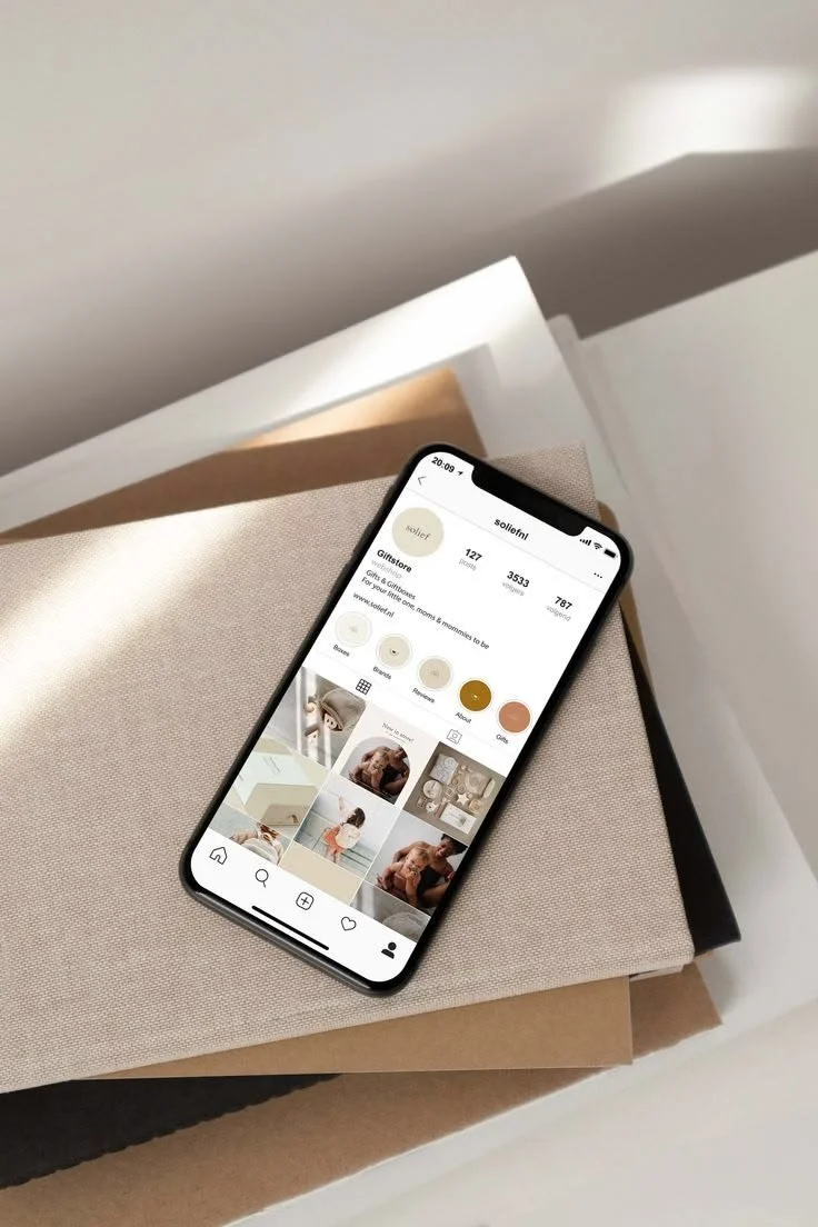 Smartphone showing a social media profile for 'sollie1' on a beige fabric surface with neutral-colored boxes underneath.