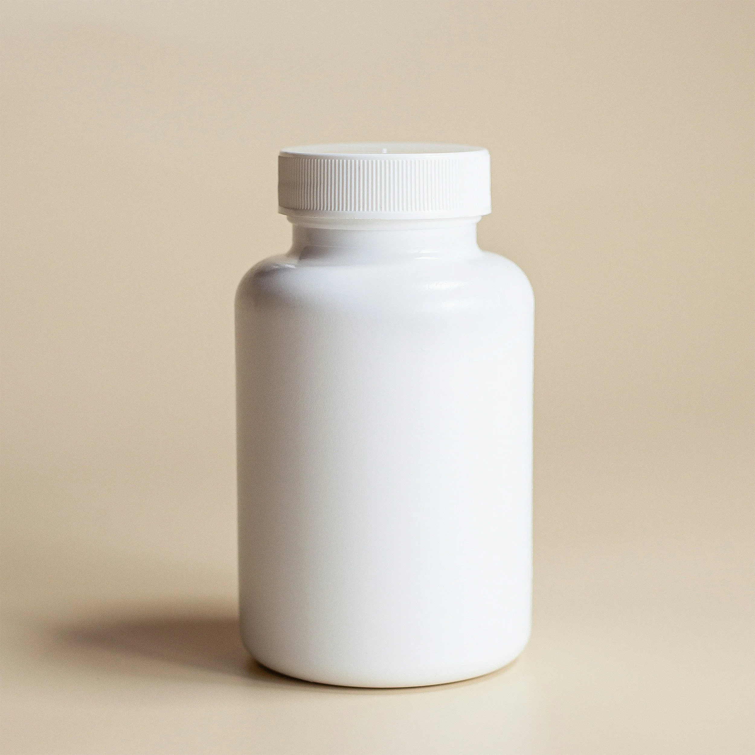 Close-up of a white plastic bottle with a ribbed screw cap on a beige background.