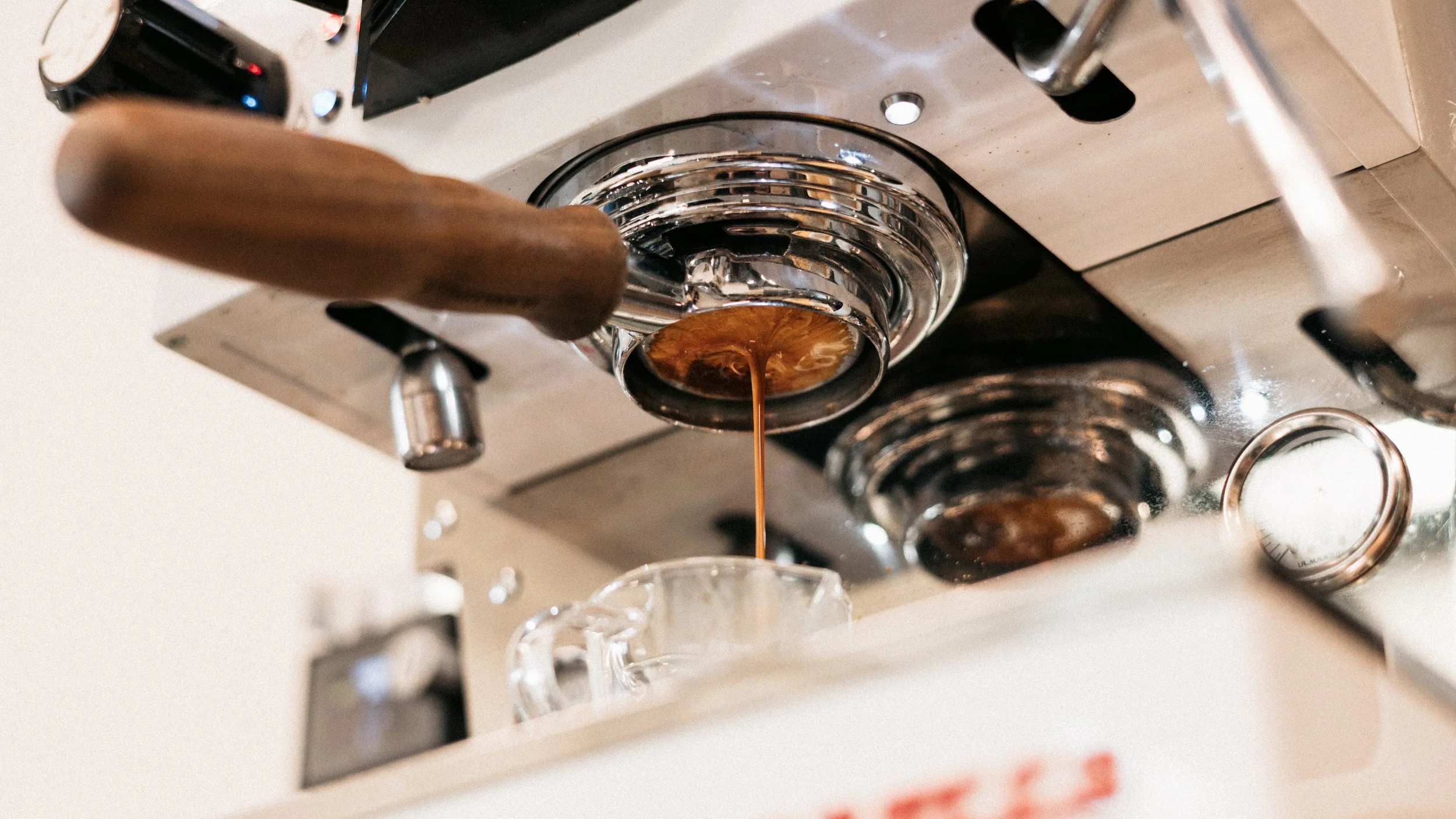 Close-up view of a coffee machine dispensing hot coffee into a glass cup.