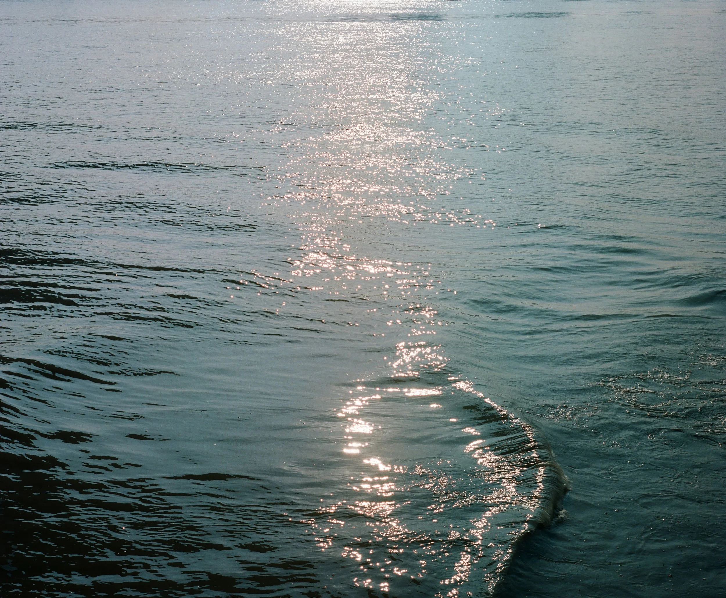 Sun reflecting off calm ocean water with gentle ripples.