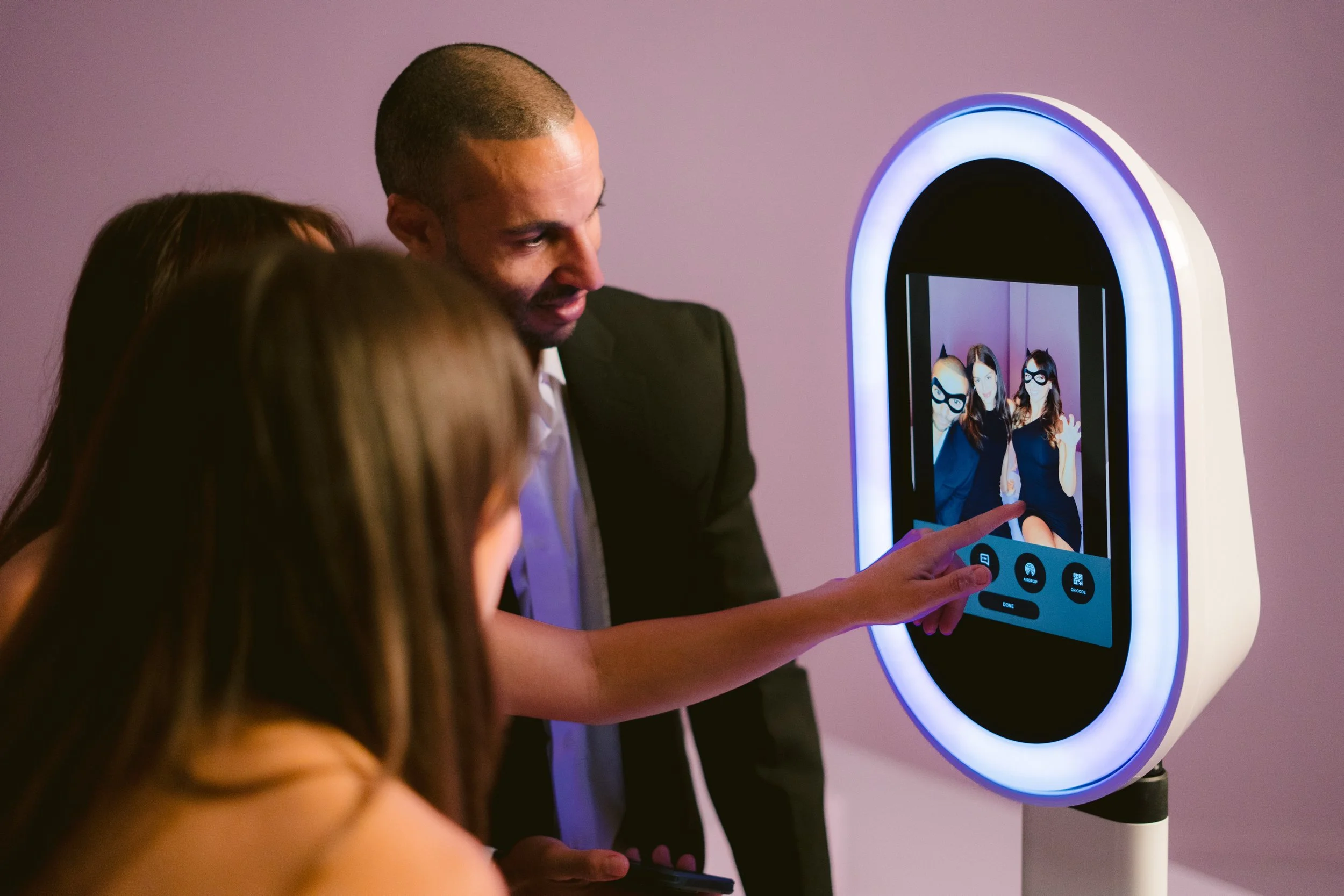 People taking a photo of themselves in a mirror with a photo booth or photo station.