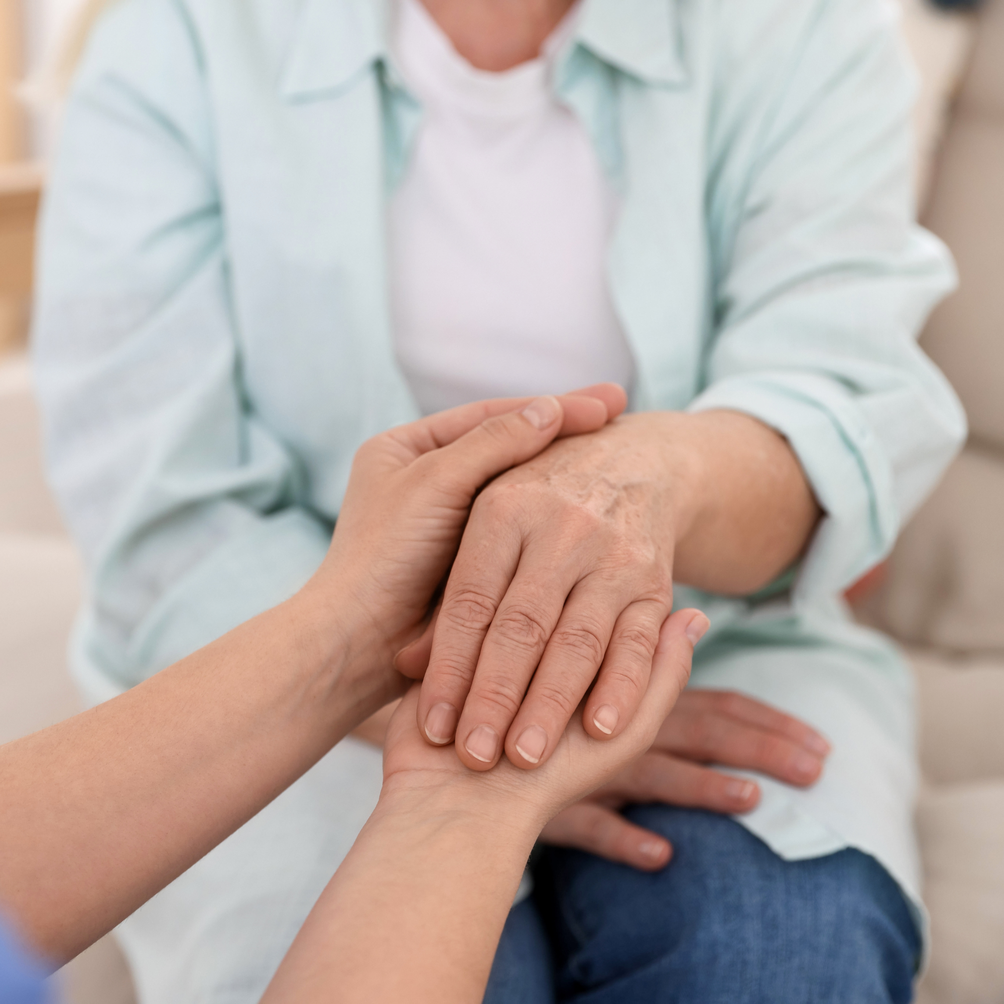 Multiple hands gently holding each other in a supportive gesture.