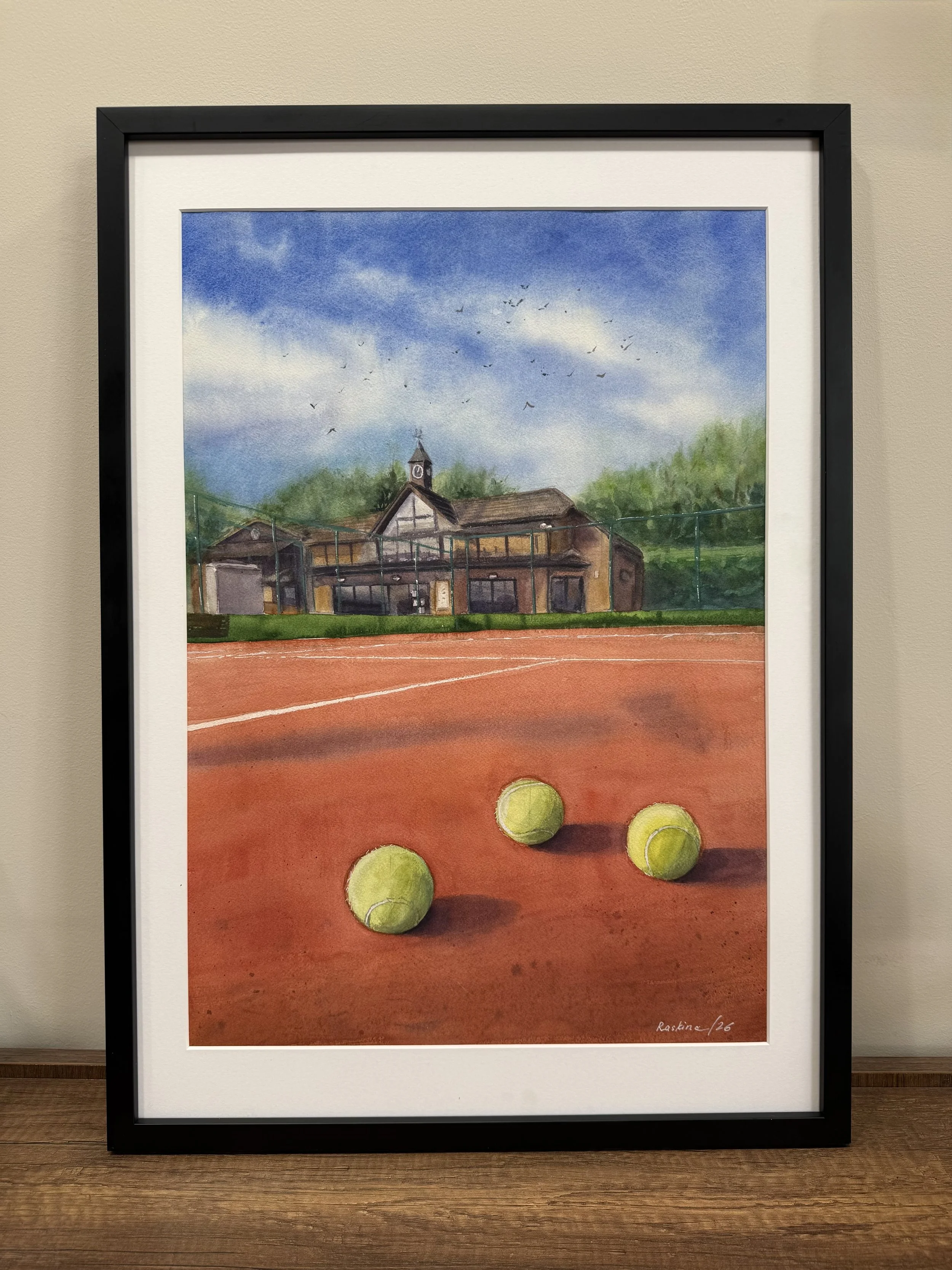 Framed HLTC Clubhouse under Blue Sky watercolour painting displayed on a wooden surface