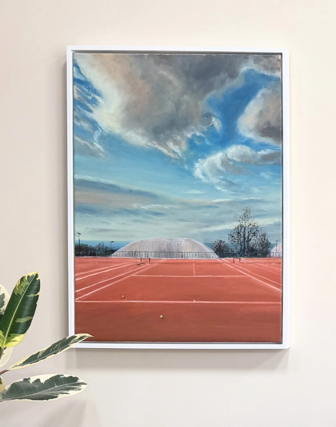 Framed Court 16 in Winter oil painting displayed on a light wall beside a green houseplant