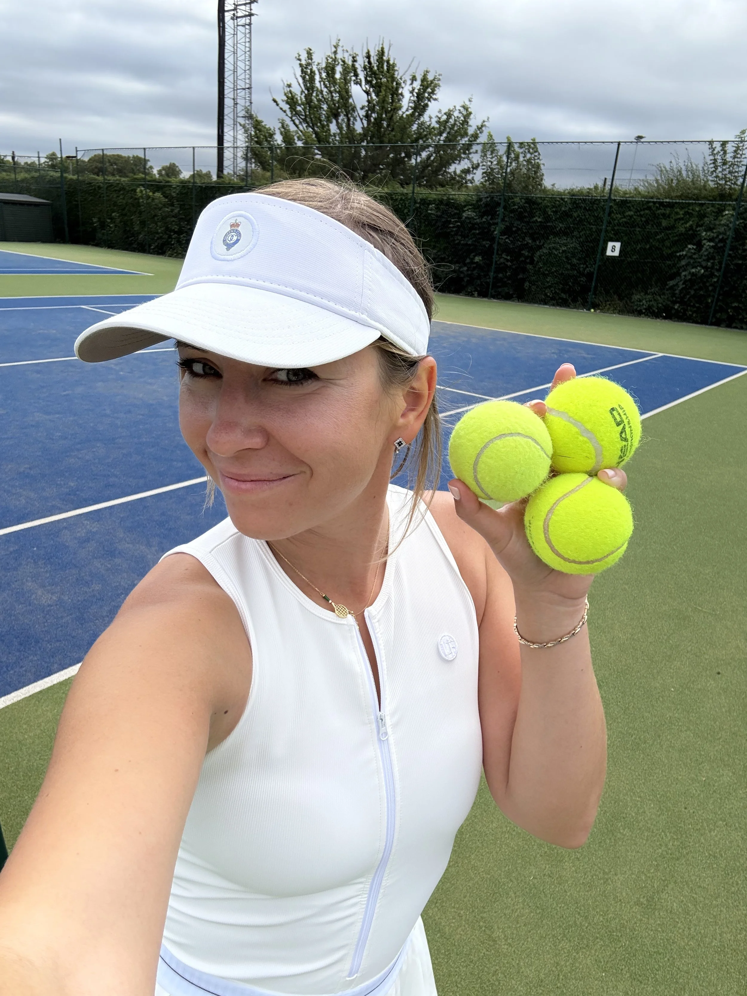 Maria Raskina on a tennis court holding a few tennis balls