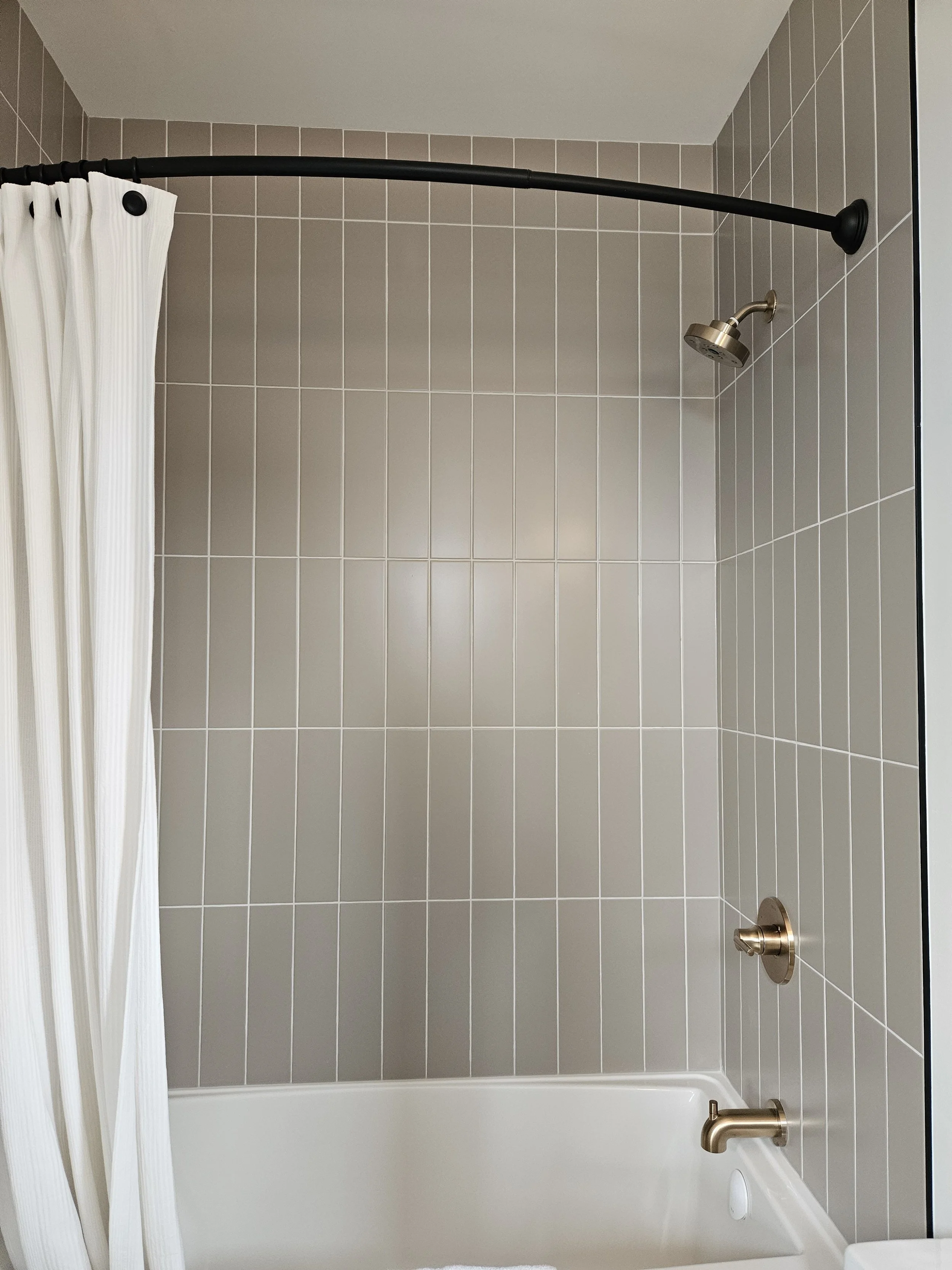 Bathroom remodel with a vanity, mirror, glass-enclosed shower with tiled walls.