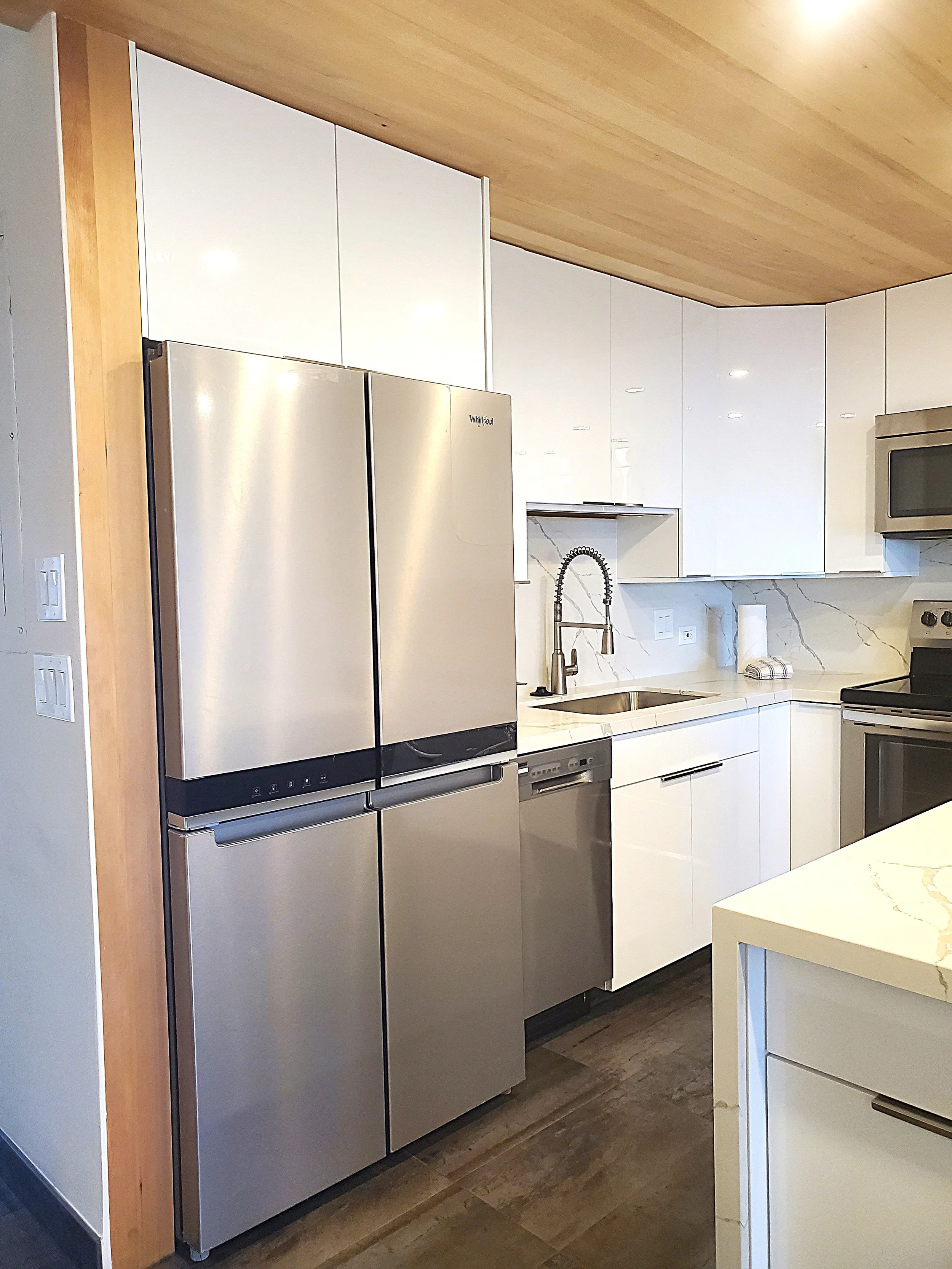 After: Kitchen remodel with custom modern white cabinets, granite countertops and backsplash, tile floors, stainless-steel appliances. 