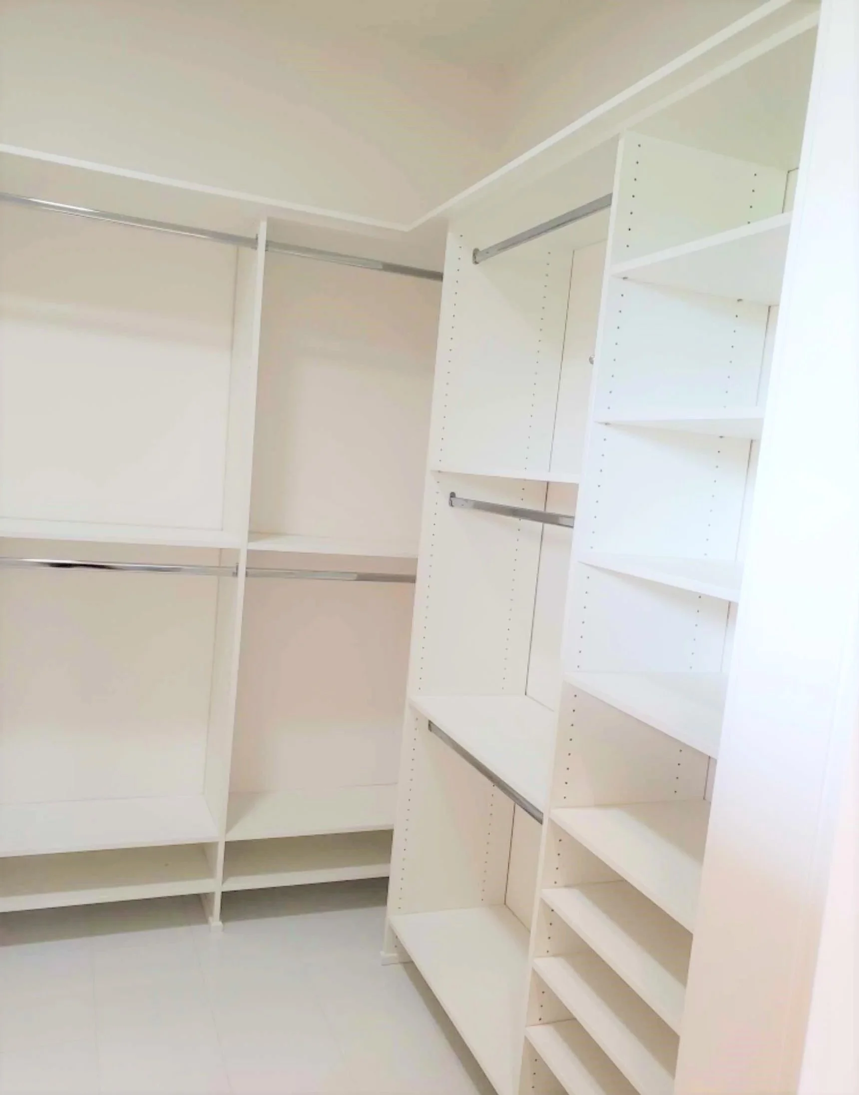 Custom build of white closet with multiple shelves and hanging rods.