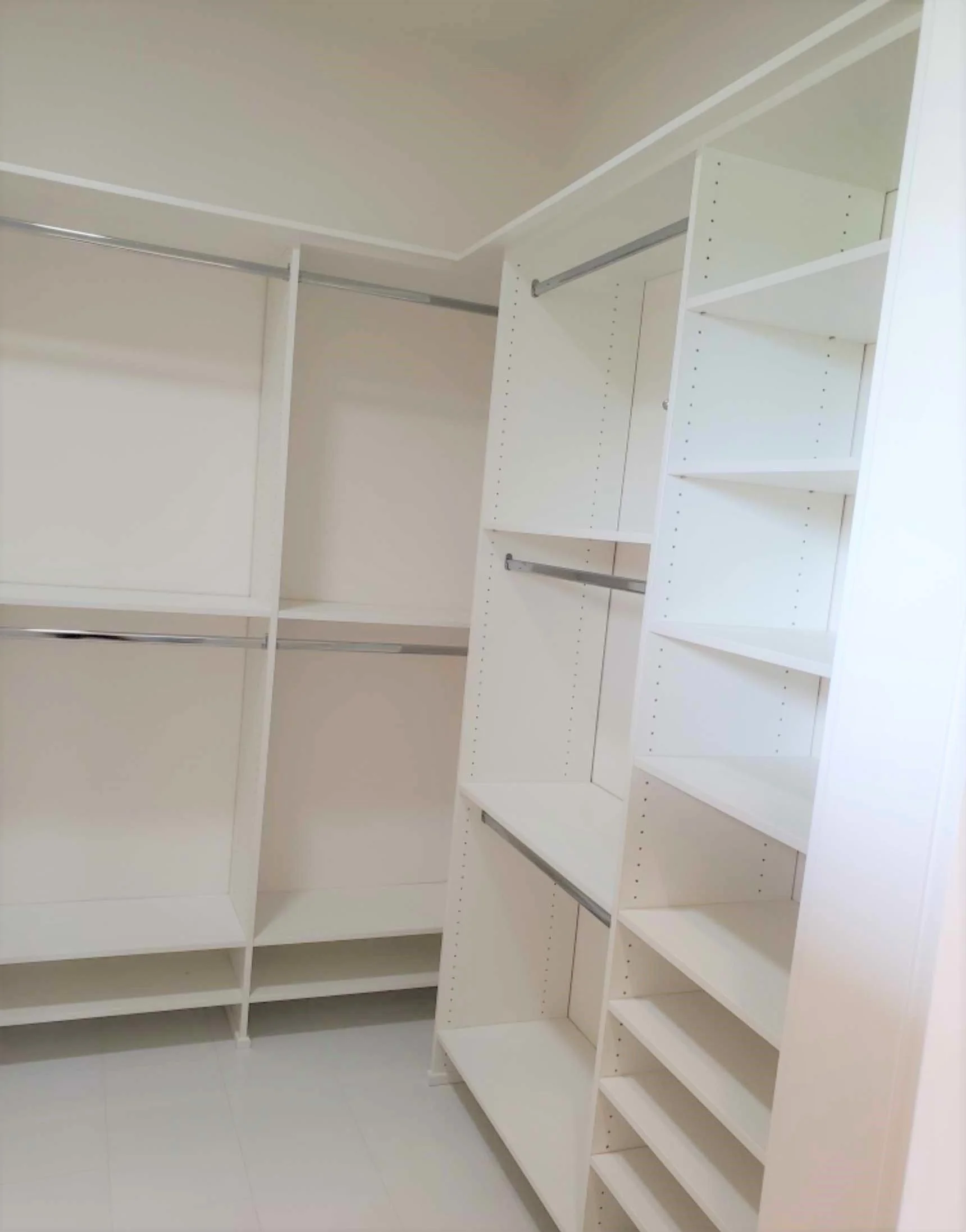 Custom build of white closet with multiple shelves and hanging rods.