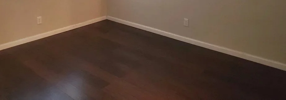 Installation of new dark hardwood flooring, and white baseboards.