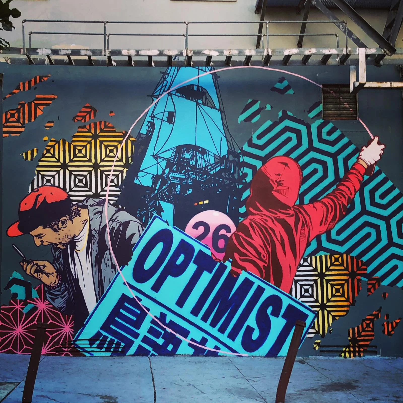 A colorful mural with a person in a red hoodie reaching up, a man in a cap looking at his phone, and various geometric patterns, including a silhouette of a tall ship, Bay Area street art, San Francisco street art, murals,  @optimistneverdies