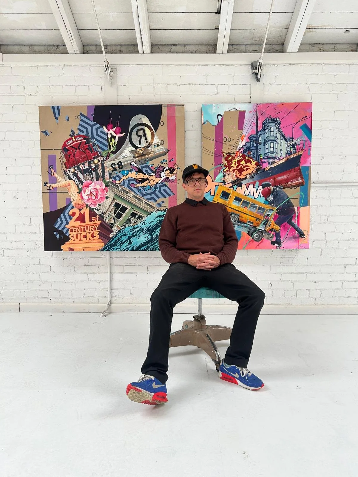 Bay Area street artist Timothy Williams (Optimist) seated in front of his colorful graffiti-style painting of a chaotic urban scene with a bus and fire, San Francisco, local art, street art, @optimistneverdies.