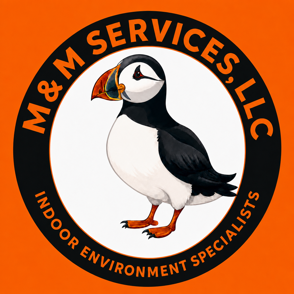 Logo featuring a puffin with a bi-colored beak, standing on orange feet, inside a circular black border with the text 'M&M SERVICES, LLC' on top and 'INDOOR ENVIRONMENT SPECIALISTS' on the bottom, set against an orange background.