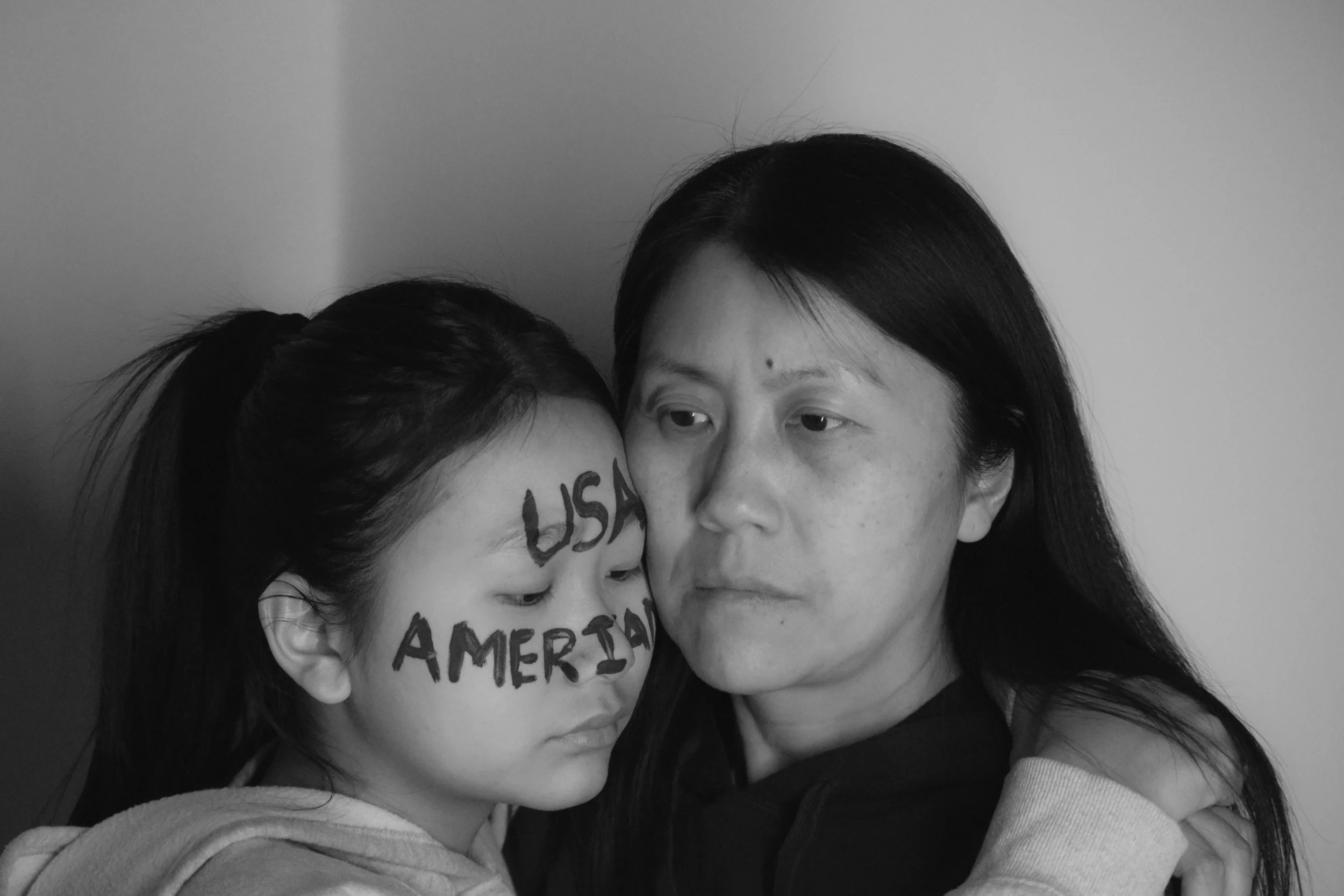Branded Divide, 20x13.3, 2025. Digital camera captures the word "American" imprinted onto my face using face paint. I am American, mom is Chinese. We will always be different.