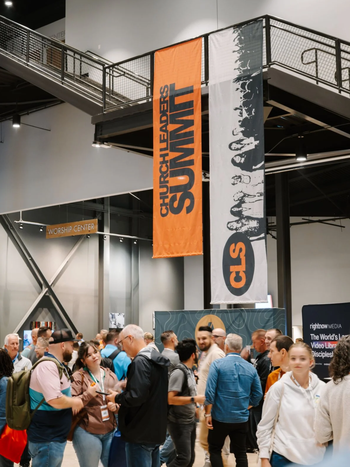 Crowd gathered at a church leaders summit with banners for Click Church, showing a group of people engaging in conversations at an indoor event.