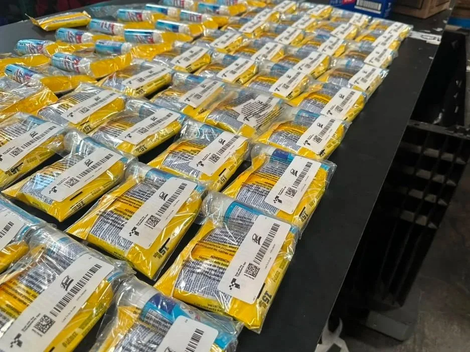 Rows of packaged laundry detergent pods on a black table in a warehouse or store.