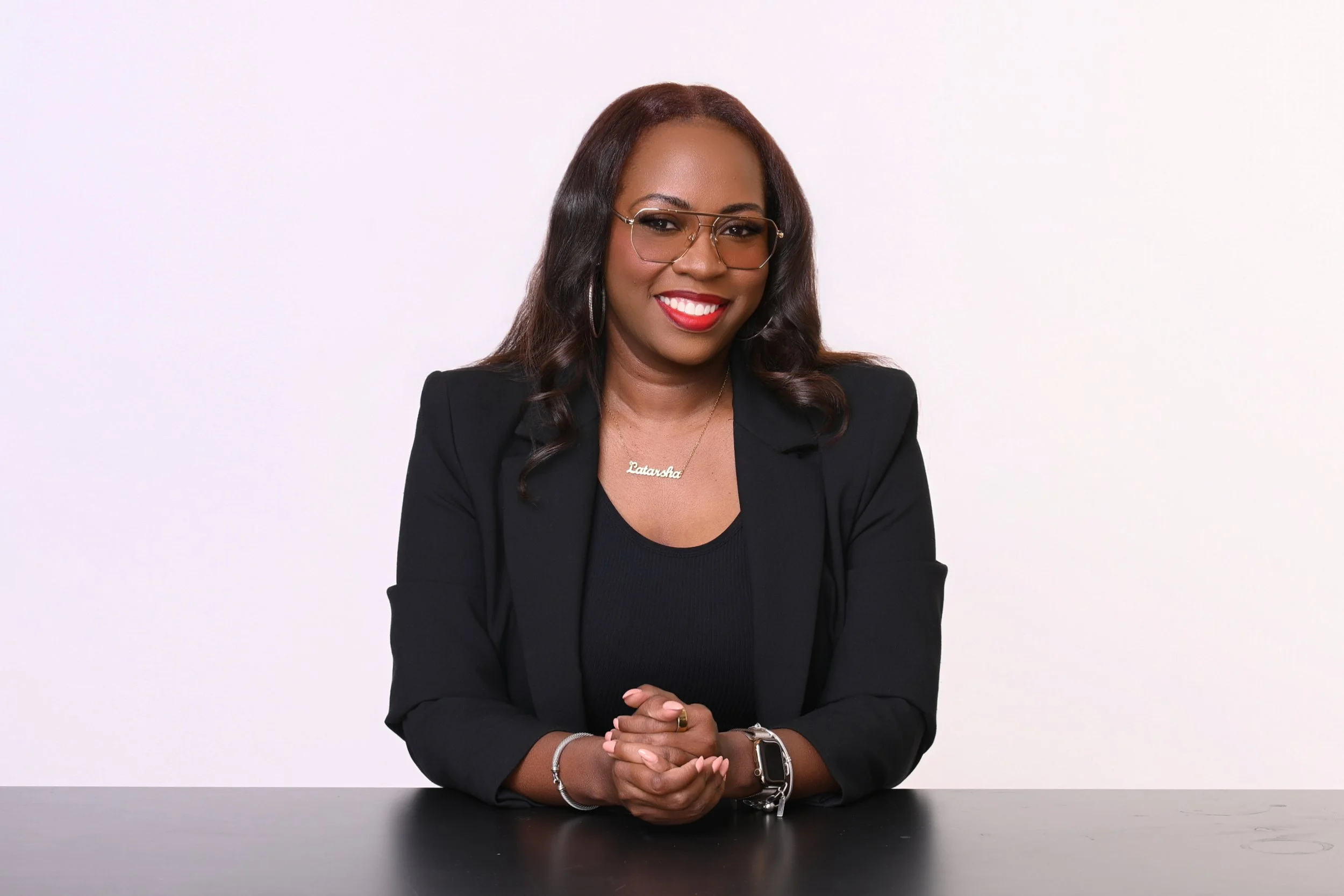 Latarsha, founder of Seen & Developed Co., smiling while seated at a table in a black blazer.