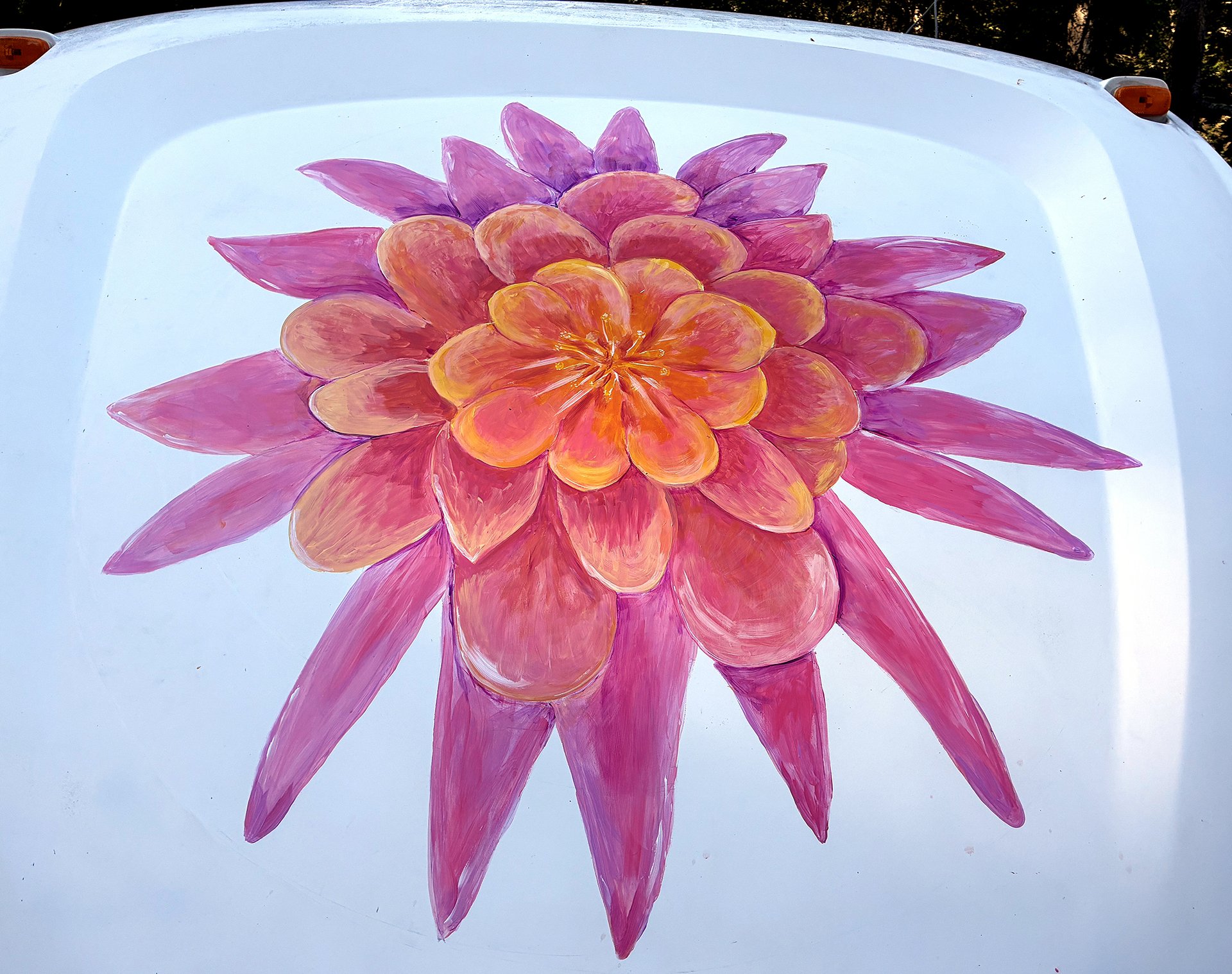 Close-up of a finished hand-painted dahlia flower mural in pink and orange on the front of a white RV.