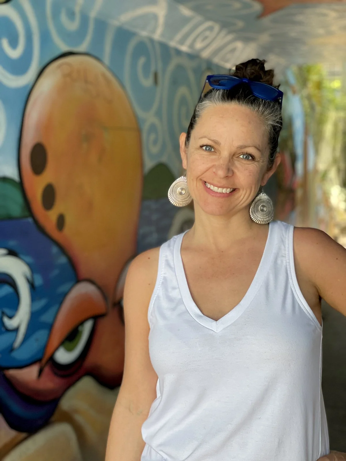 Darcy Ballew, a Kirkland art teacher, smiling in front of a colorful mural.