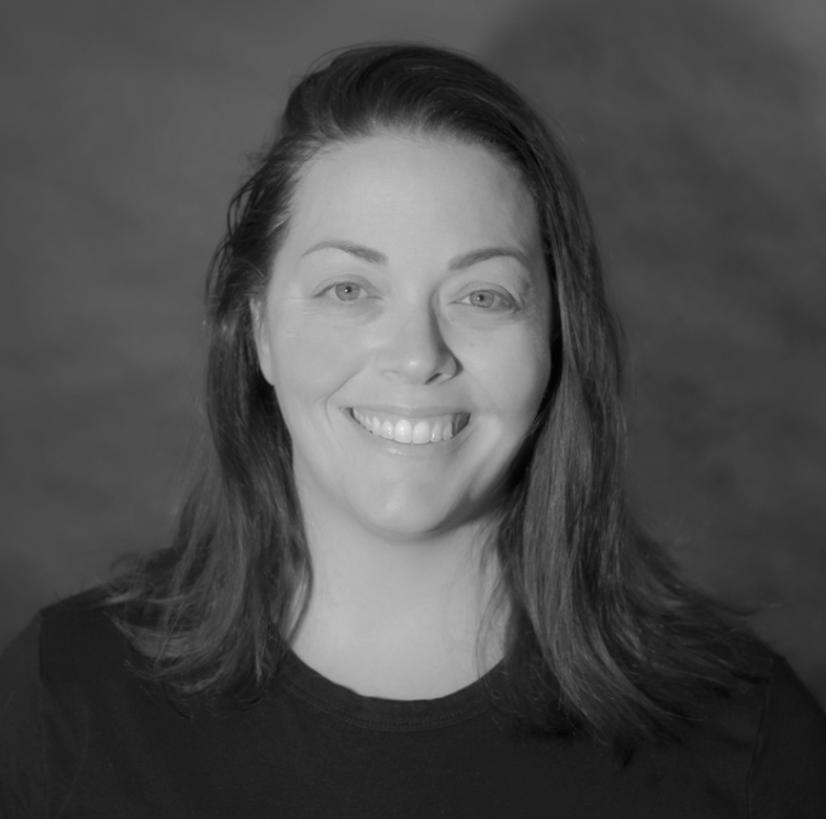A woman with shoulder-length dark hair, smiling, wearing a black shirt, against a plain background.