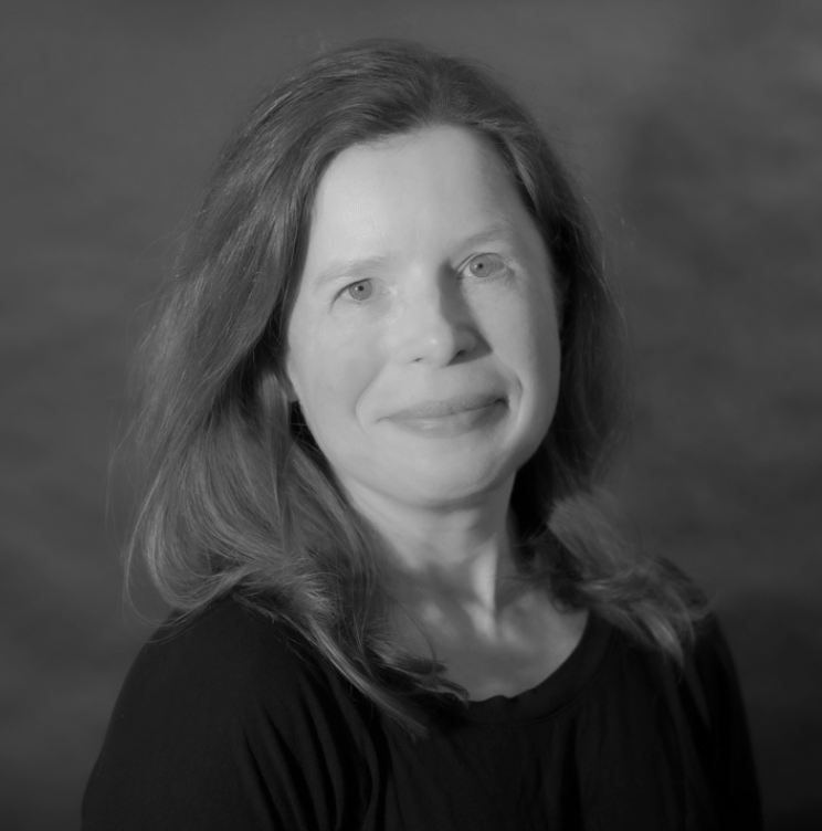 Black and white portrait of a woman with shoulder-length hair, wearing a dark top, smiling gently, with a blurred background.