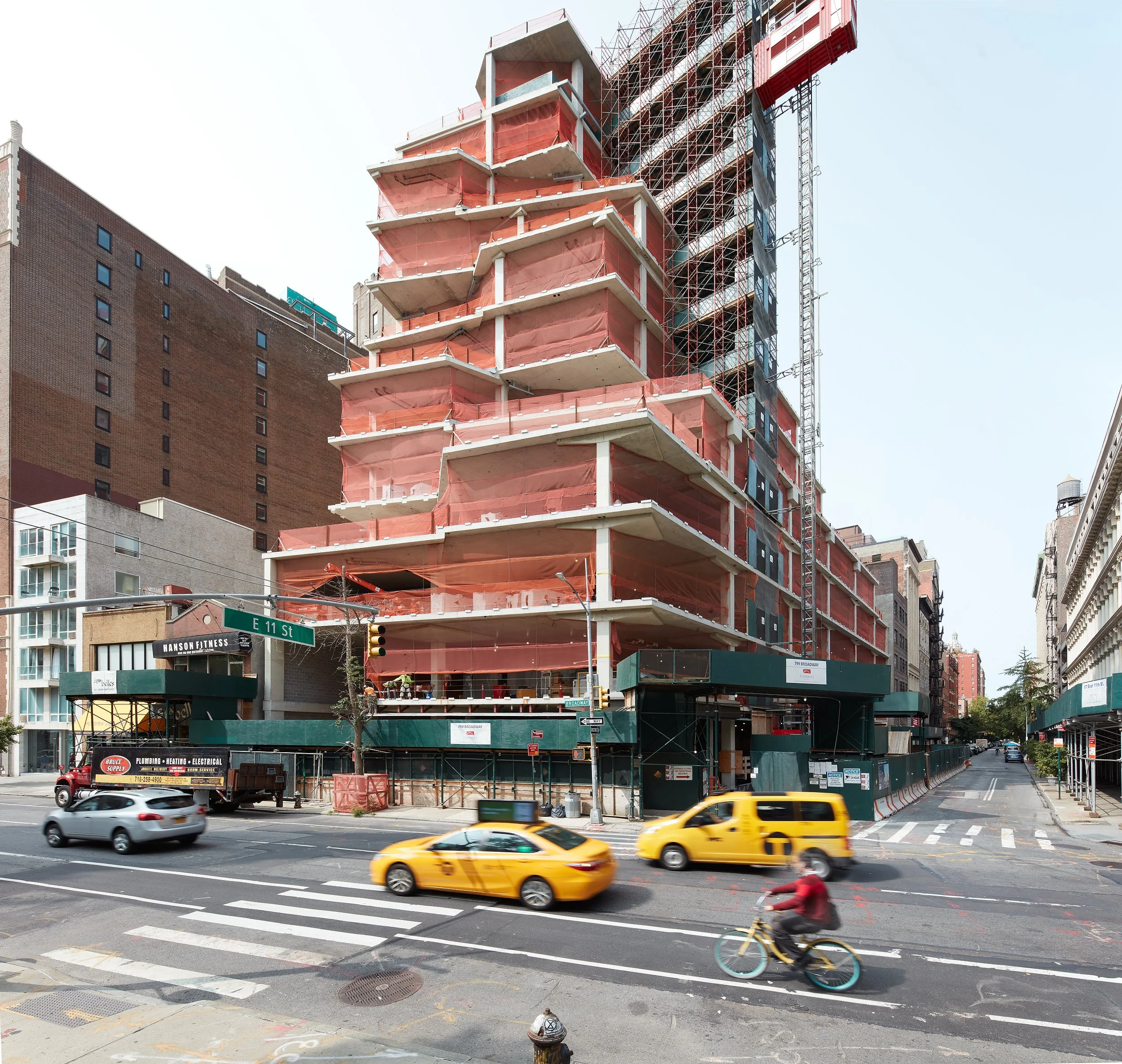 A multi-story building under construction with exposed floors, surrounded by scaffolding. Capturing the energy of the site, this example of construction photography also serves as valuable photograph documentation. 