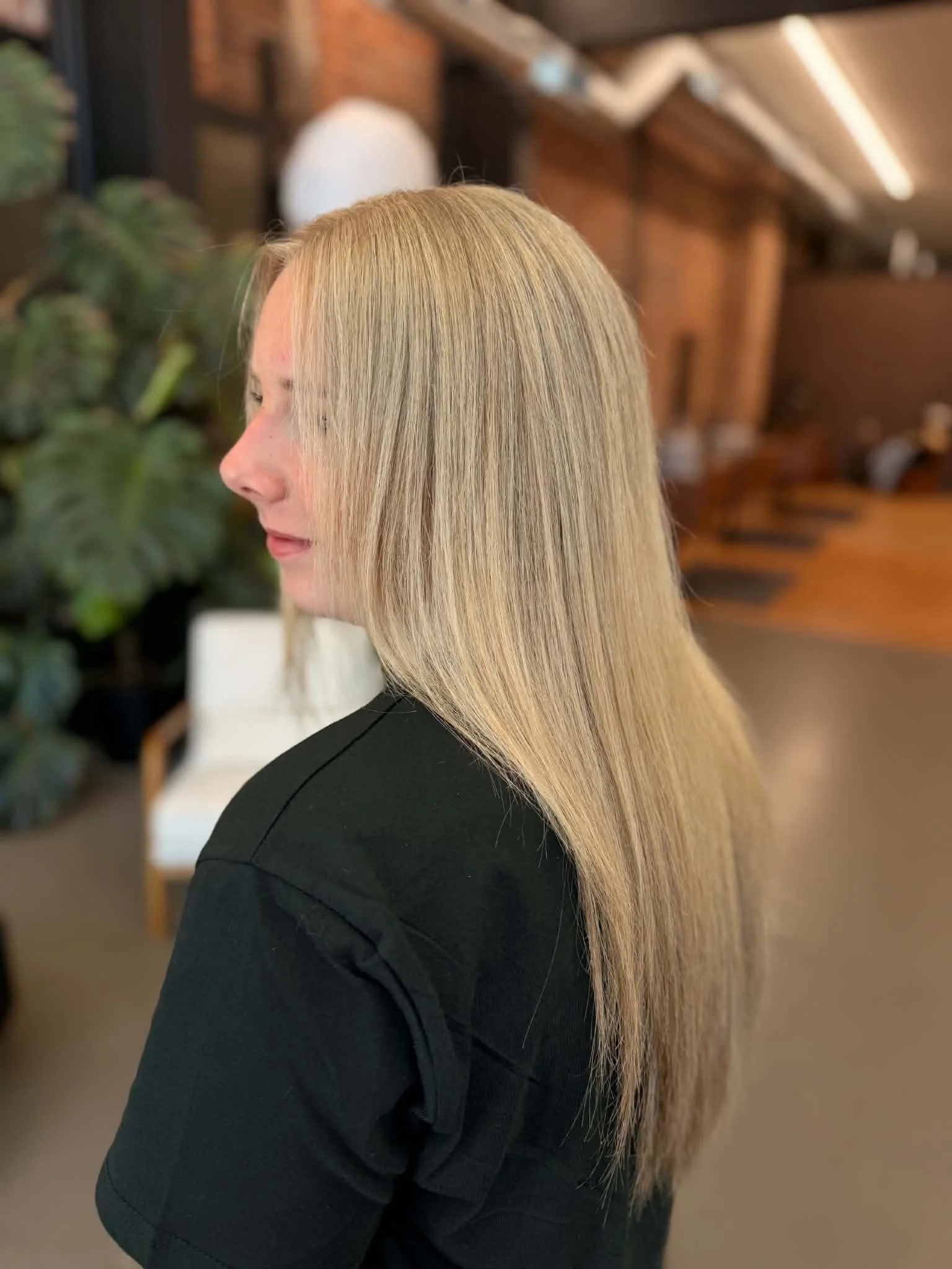 Woman with long, straight blonde hair in a salon or similar setting.