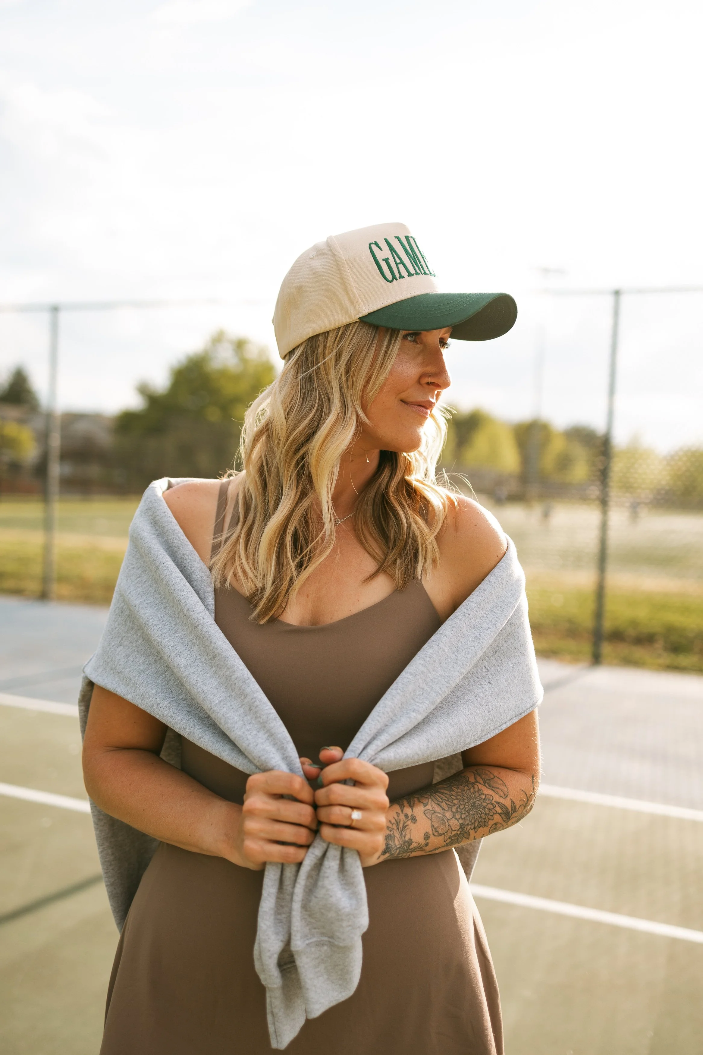 Malia Reynolds, blonde hairstylist and colorist behind Wildewood Hues, wearing a cap on the pickleball court